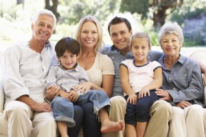 Three Generation Family Sitting On Sofa At Home