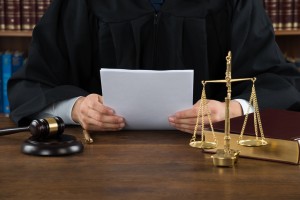 Midsection of judge reading documents at desk in courtroom